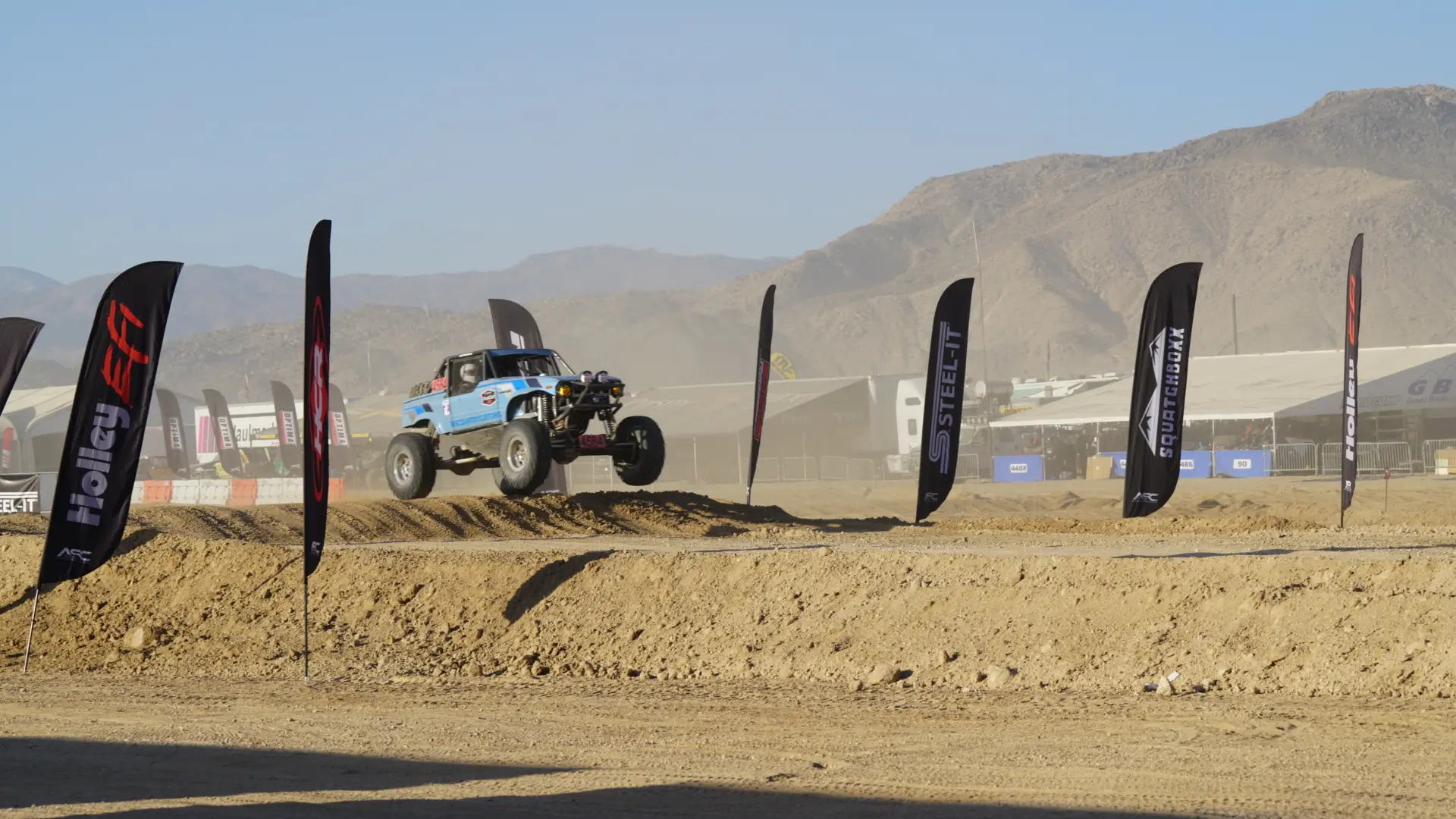 a blue color car jumping on the pile of soil